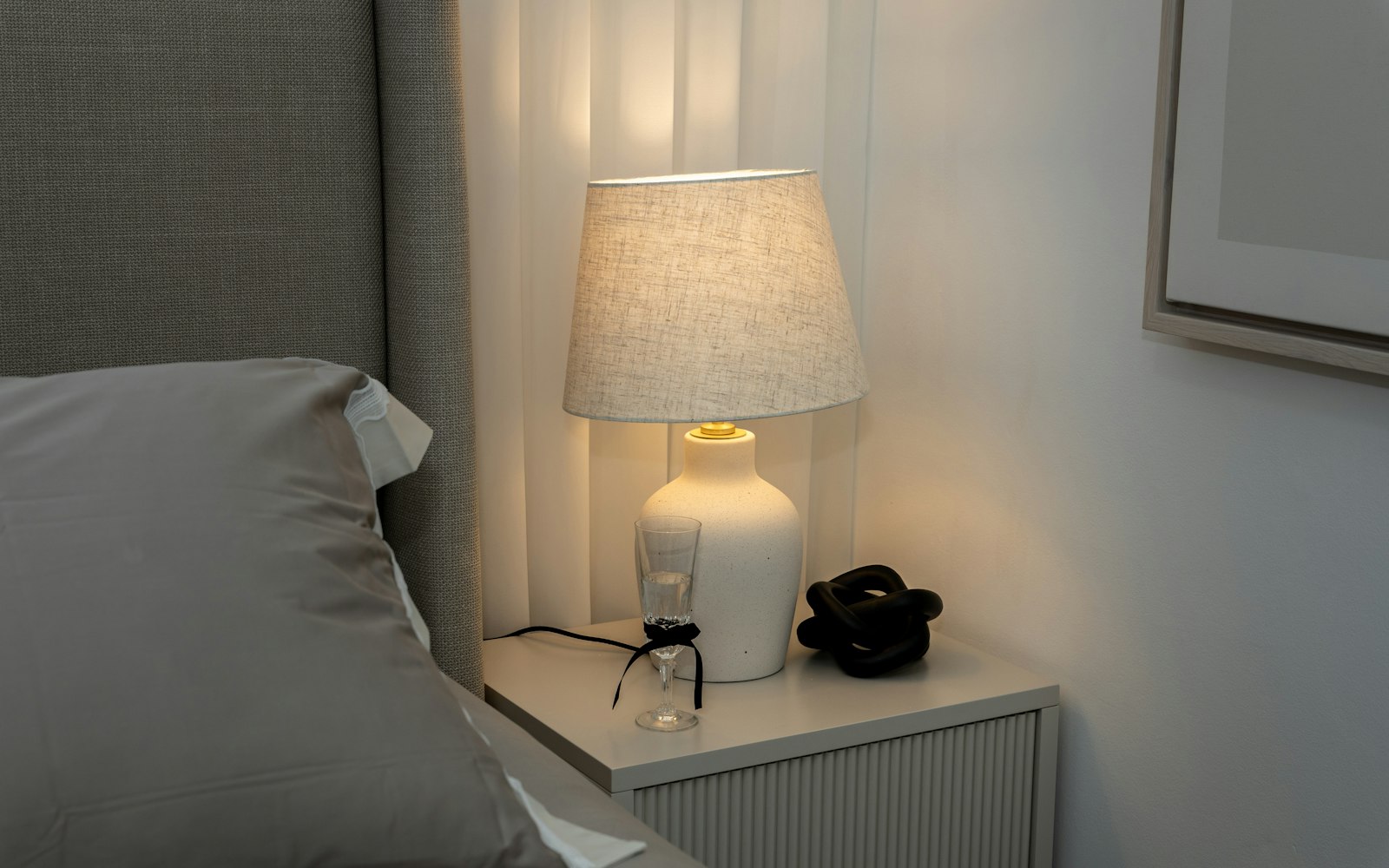 A softly lit bedside lamp beside a bed, a setting for a night skincare routine